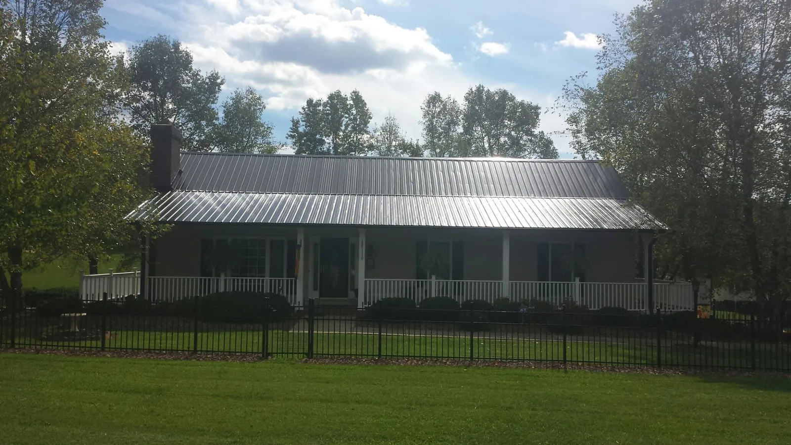 Gray metal roof on a brick ranch with a full width front porch — Gutter Guard Installation work by our crew in Clio